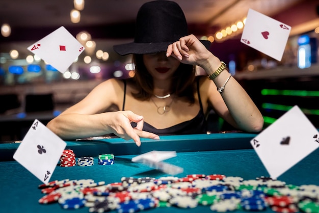 Pretty woman in evening black dress plays poker in the casino