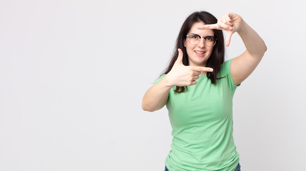 Pretty woman feeling happy, friendly and positive, smiling and making a portrait or photo frame with hands