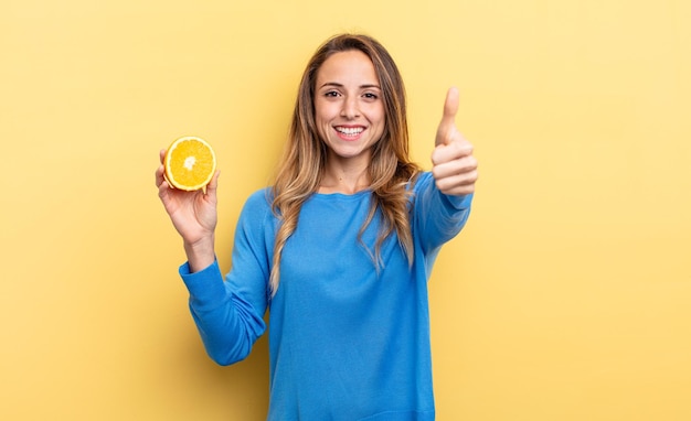 Pretty woman feeling proud,smiling positively with thumbs up holding half orange