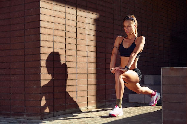 Pretty woman in good shape doing stretching in the city park outdoors copyspace sport lifestyle