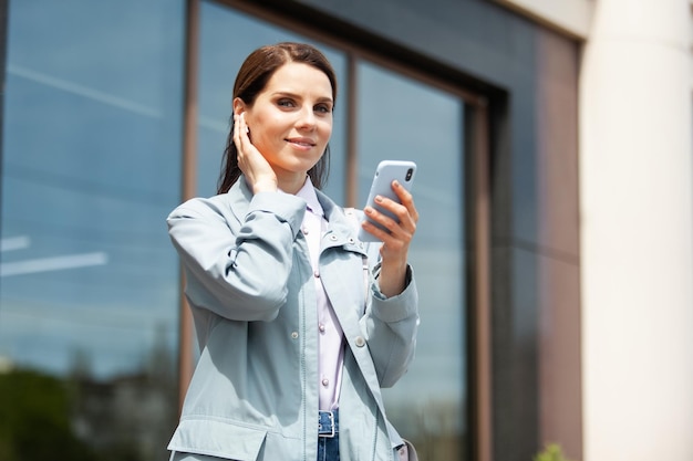 Pretty woman in headphones holds a smartphone in the town Lifestyle