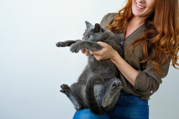 Pretty woman holding her russian blue cat in hands