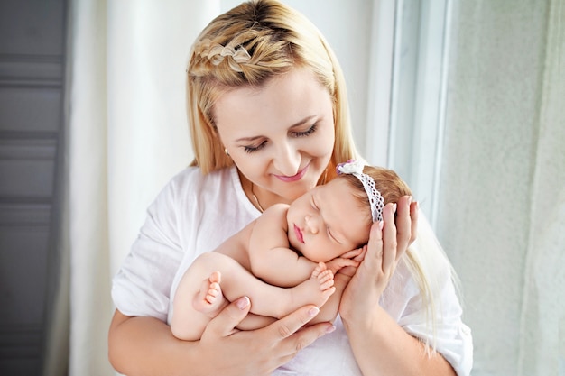 Pretty woman holding a newborn baby girl in her arms. Happy mother and her slipping newborn baby.  Happy family concept