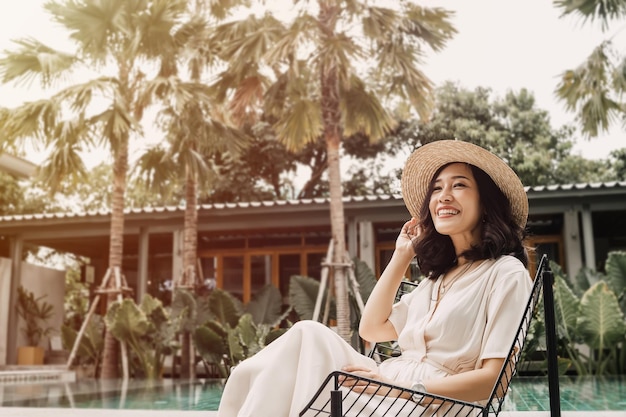 Pretty woman is sitting near swimming pool She is happy