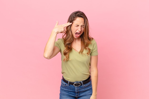 Pretty woman looking unhappy and stressed, suicide gesture making gun sign