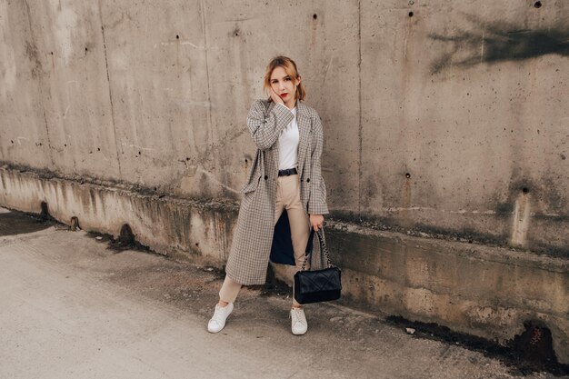 Pretty woman posing near gray wall. Girl dressed casual outfits with red lips