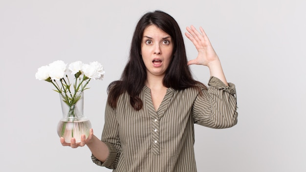 Pretty woman screaming with hands up in the air and holding a decorative flowers. assistant agent with a headset