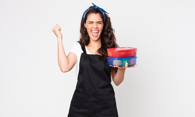 Pretty woman shouting aggressively with an angry expression and holding tupperwares with food