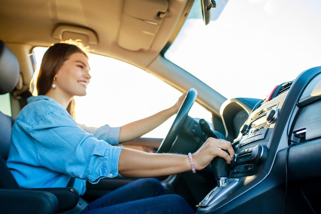 Pretty woman singing while driving a car on road trip on summer day