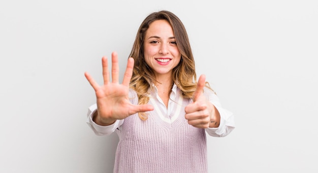 Pretty woman smiling and looking friendly showing number six or sixth with hand forward counting down