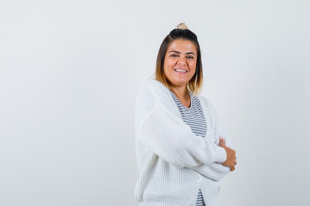 Pretty woman standing with crossed arms in t-shirt, cardigan and looking glad