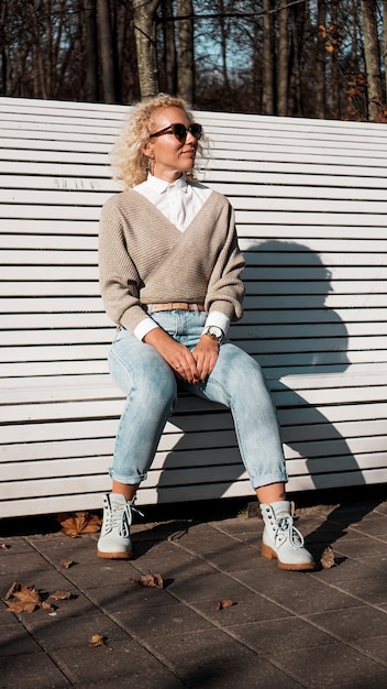 Pretty woman in sunglasses on bench at autumn park alone, lifestyle people concept