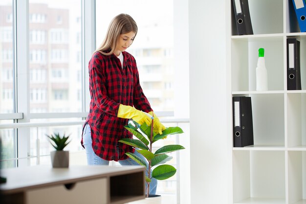 Pretty woman in uniform with supplies cleaning in office.