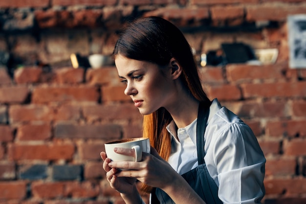 Pretty woman waiter holding mug brick wall restaurant