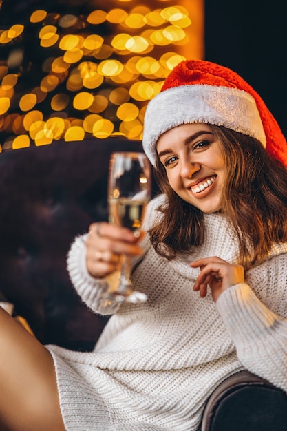 Pretty woman in warm sweater, socks and Christmas hat, sitting on the floor