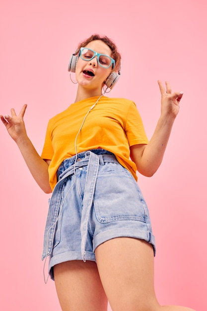 Pretty woman wearing blue glasses listening to music on headphones isolated backgrounds unaltered