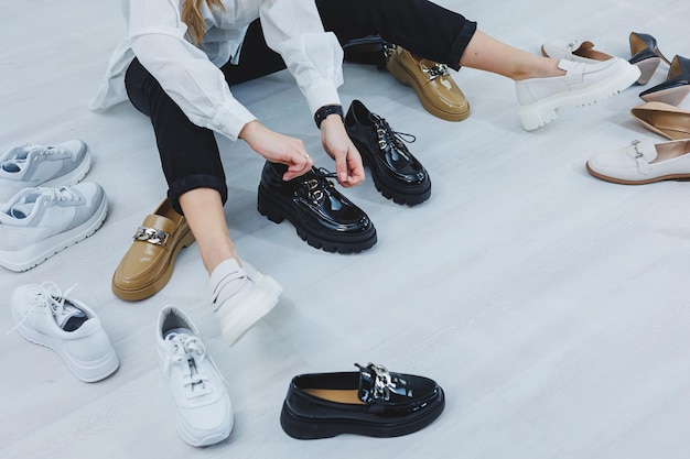 A pretty woman in a white shirt sits among her shoes Many women's shoes