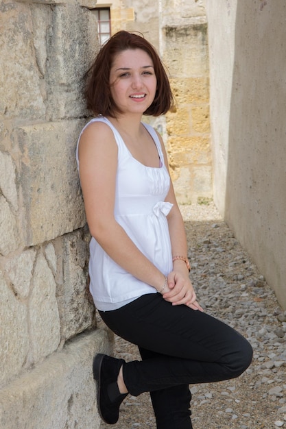 Pretty woman in white shirt standing near a brick wall