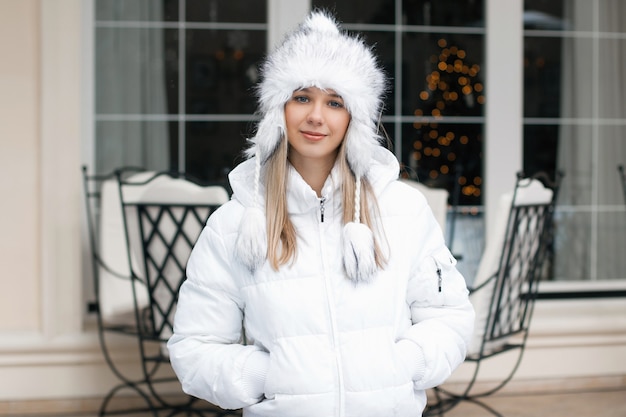 Pretty woman in the winter jacket standing near the cafe