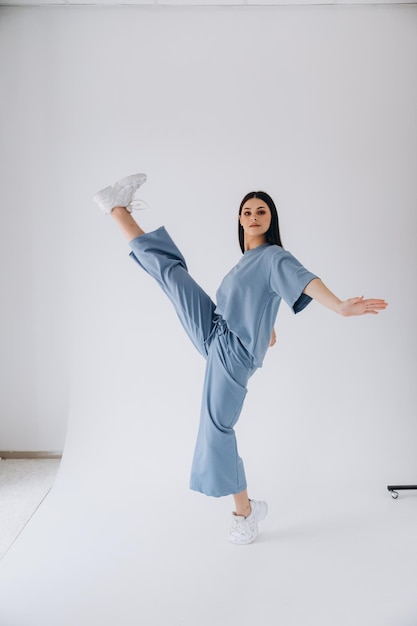 pretty woman with dark long hair posing for a photo dressed in a light blue casual suit with pants