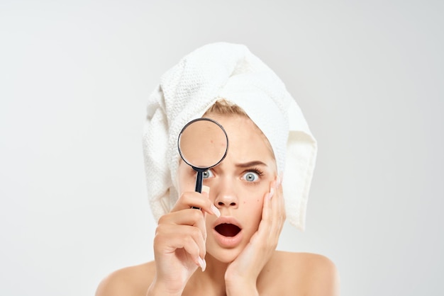 Pretty woman with towel on head face close up dermatology magnifier near face