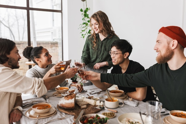 Pretty woman with wavy hair standing near table dreamily spending time with colleagues