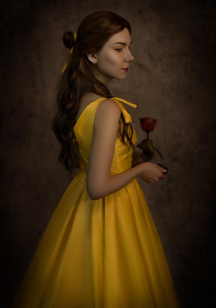 Pretty woman in the yellow dress closeup with red rose in her handsBeauty and the beast cosplay