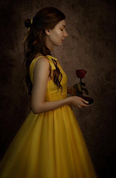 Pretty woman in the yellow dress closeup with red rose in her handsBeauty and the beast cosplay