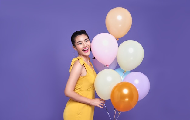 Pretty young asian woman at celebration party holding colourful balloon and smile face. Happy new year or Birthday eve celebrating concept.