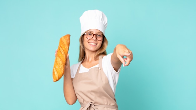 Pretty young blonde chef woman holding a bread baguette