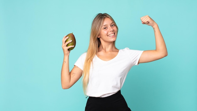 Pretty young blonde woman holding a mango