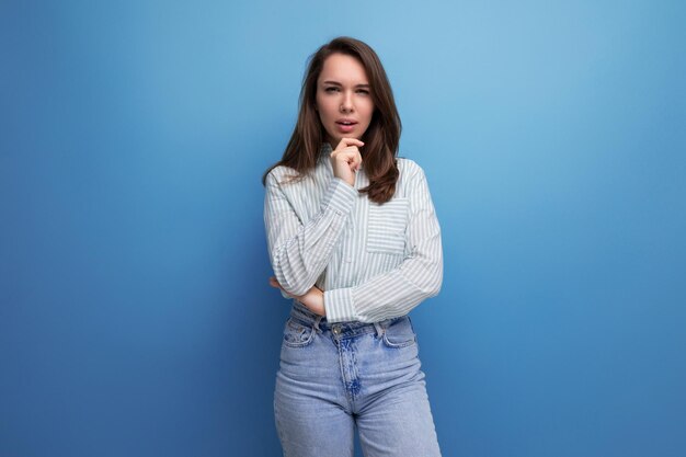 Pretty young brunette woman in shirt on studio background