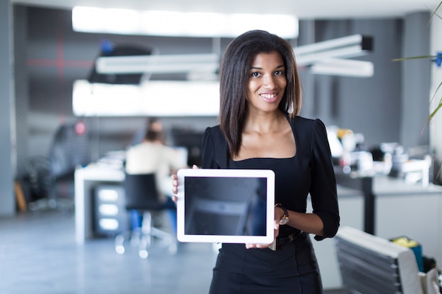 Pretty, young business lady in black strong suite hold tablet