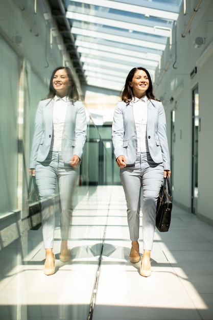 Pretty young business woman walking with briefcase in the office hallway