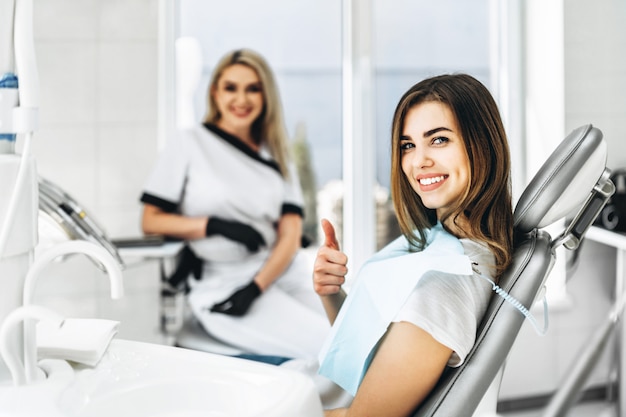 Pretty young female dentist making examination and treatment for young female patient in dental clinic.