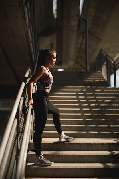 Pretty young female runner resting on stairs