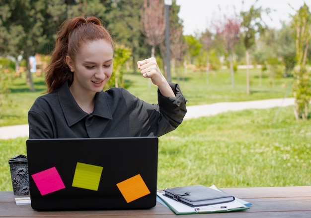 Pretty young female sitting using laptop showing super smiling