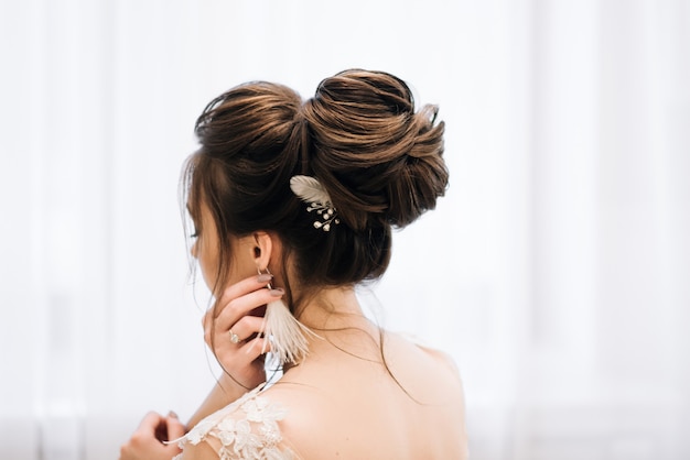 Pretty young girl.  Boudoir morning of the bride. Bride with luxurious hair and makeup. Accessories with feathers