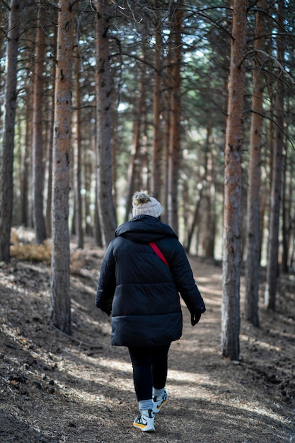 Pretty young girl bundled up in a forest in the mountains