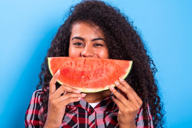 Pretty young girl holding slice of watermelon in front of her face. Portrait of smiling african american girl isolated   Healthy & Happy  