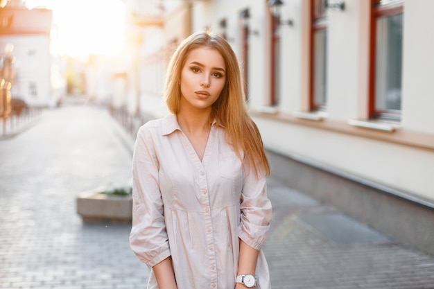 Pretty young girl in a pink shirt standing near the building