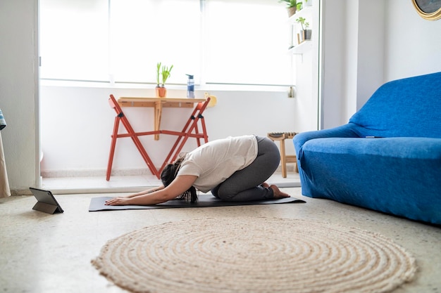 pretty young girl practicing exercise and yoga in her living room with a black cat