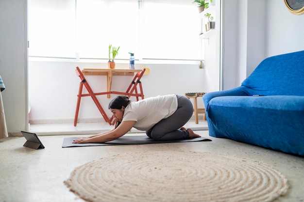 pretty young girl practicing exercise and yoga in her living room with a black cat