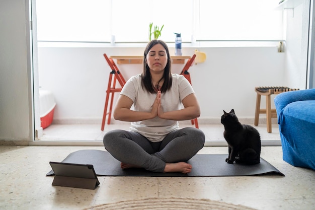 pretty young girl practicing exercise and yoga in her living room with a black cat