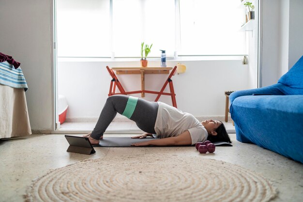 pretty young girl practicing exercise and yoga in her living room with a black cat