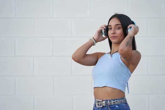 Pretty young girl putting on headphones to listen to music with her smartphone