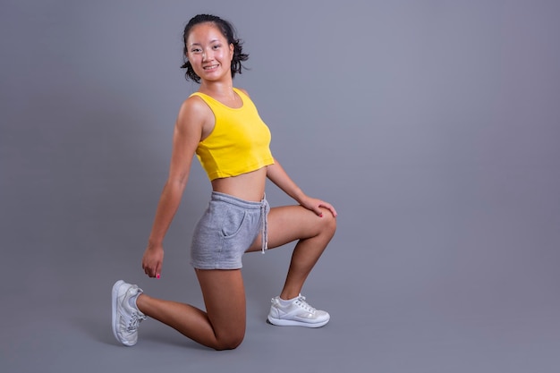 Pretty young girl in sportswear of asian ethnicity isolated on grey background