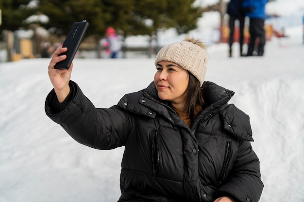 pretty young girl taking photos in the snow while enjoying