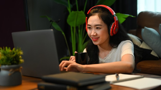 Pretty young lady wearing headphone listening lecture during study online on laptop Education elearning distance training