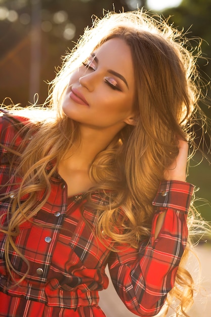 Pretty young model with closed eyes and bright glitter makeup posing at sunset